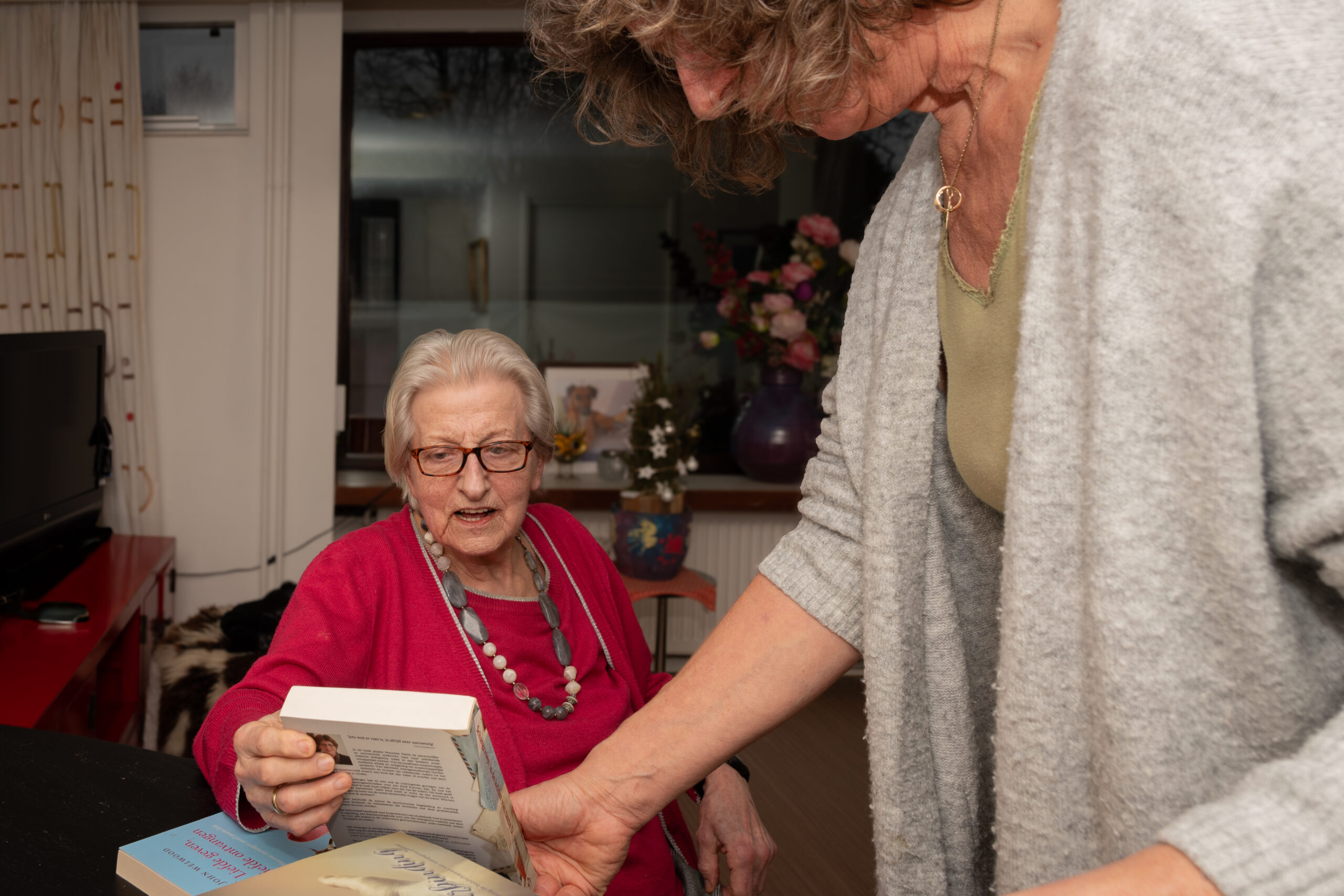 Rianne bekijkt samen met een oudere vrouw een boek
